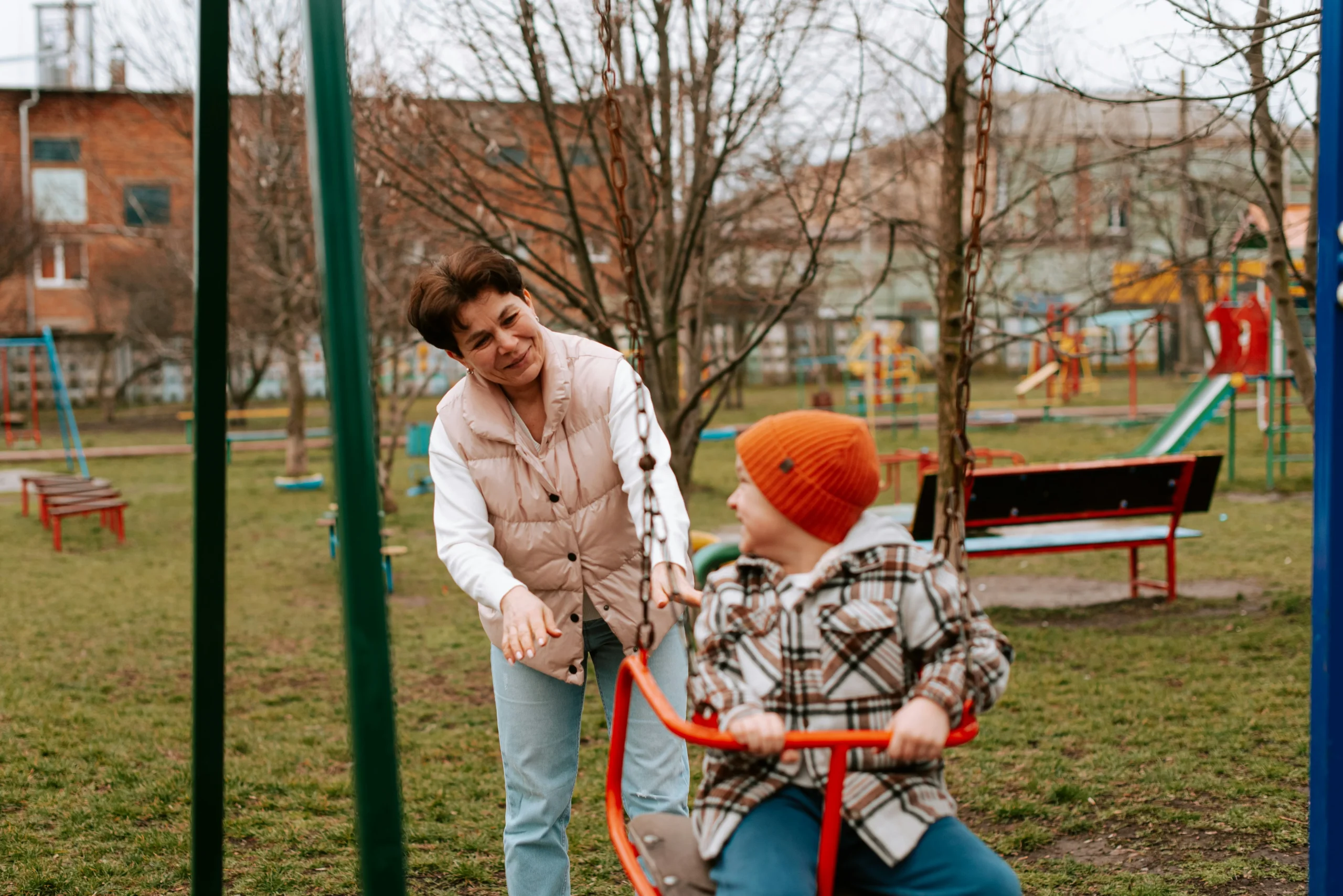 A caregiver assisting a child with special needs on a swing at the park, illustrating the need for a letter of intent for a special needs child to outline care and daily routines.