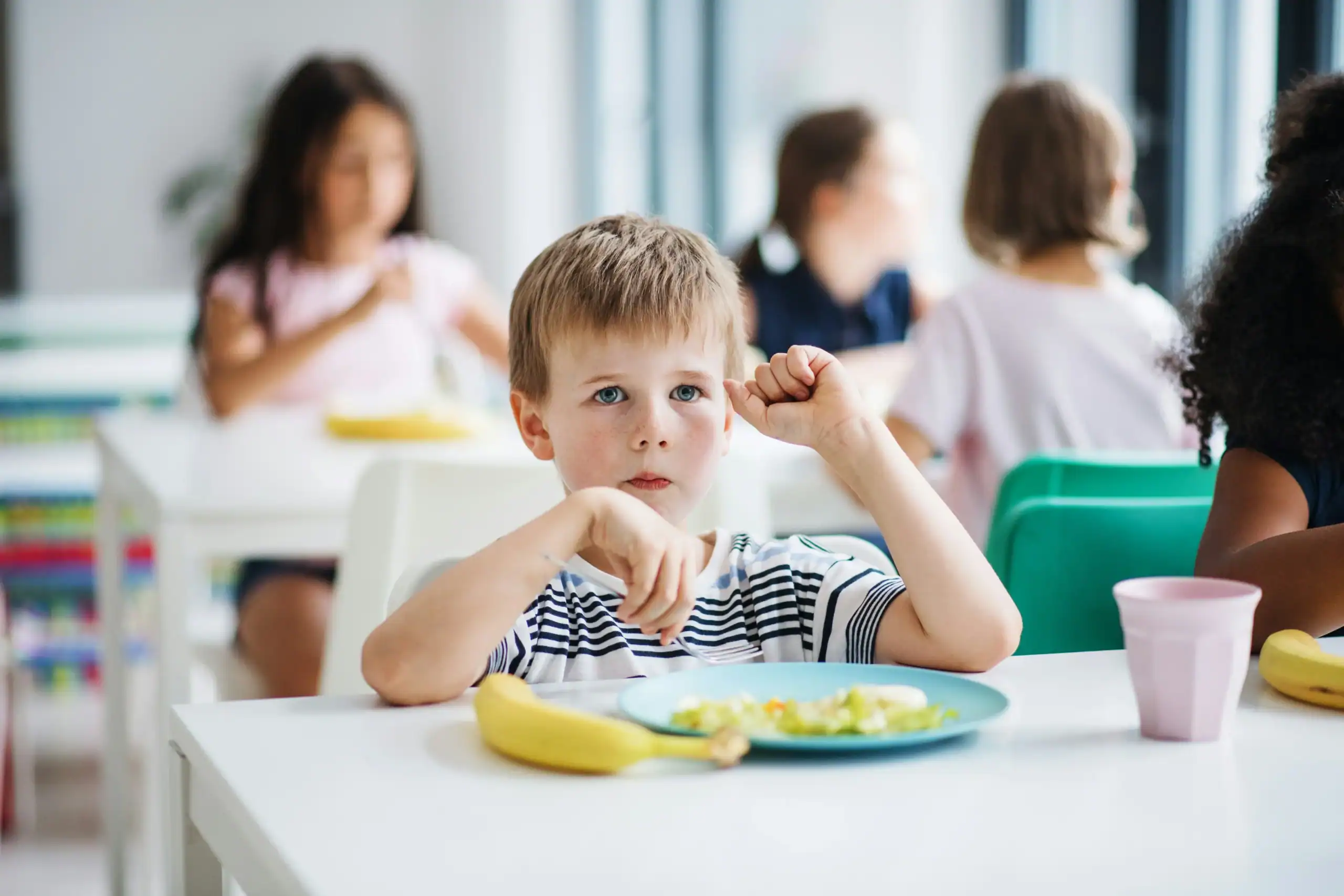 Young boy hesitating to eat lunch at school, possibly showing signs of food texture sensitivity Young boy hesitating to eat lunch at school, possibly showing signs of food texture sensitivity