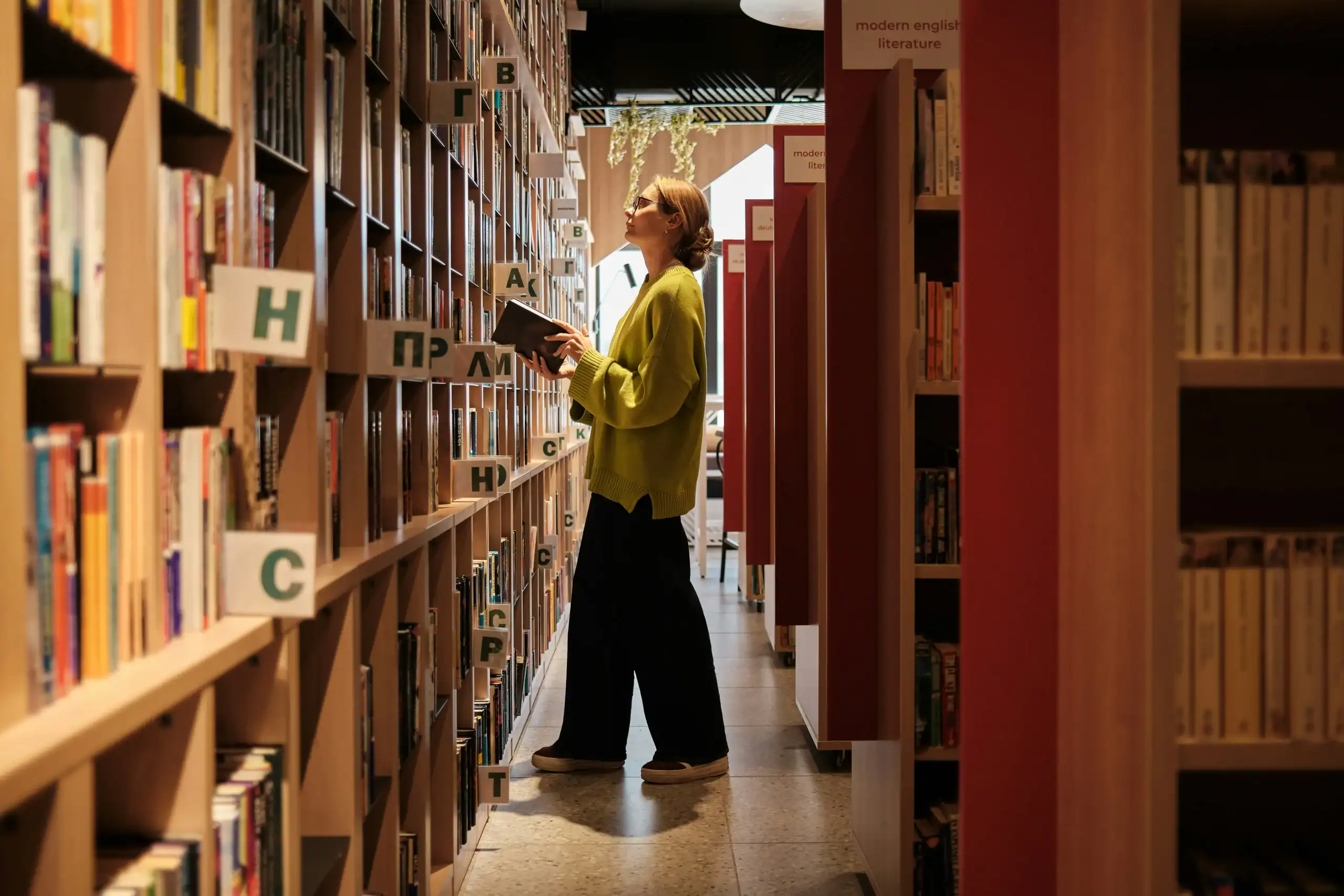 Adult woman exploring library bookshelves, demonstrating hyperlexia in adults and interest in literacy Adult woman exploring library bookshelves, demonstrating hyperlexia in adults and interest in literacy