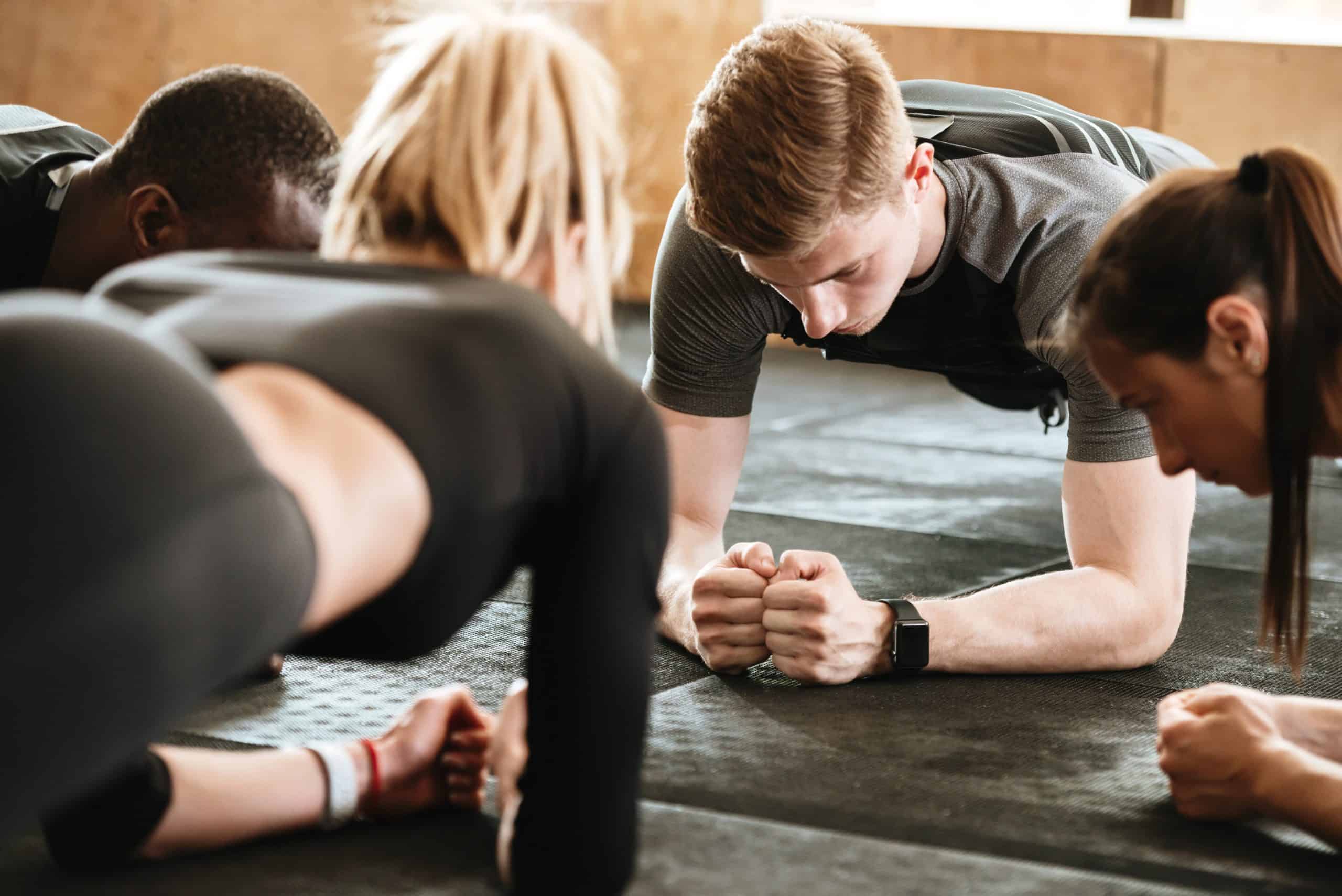 Image of group of multiethnic sports strong people make sport exercises in gym.