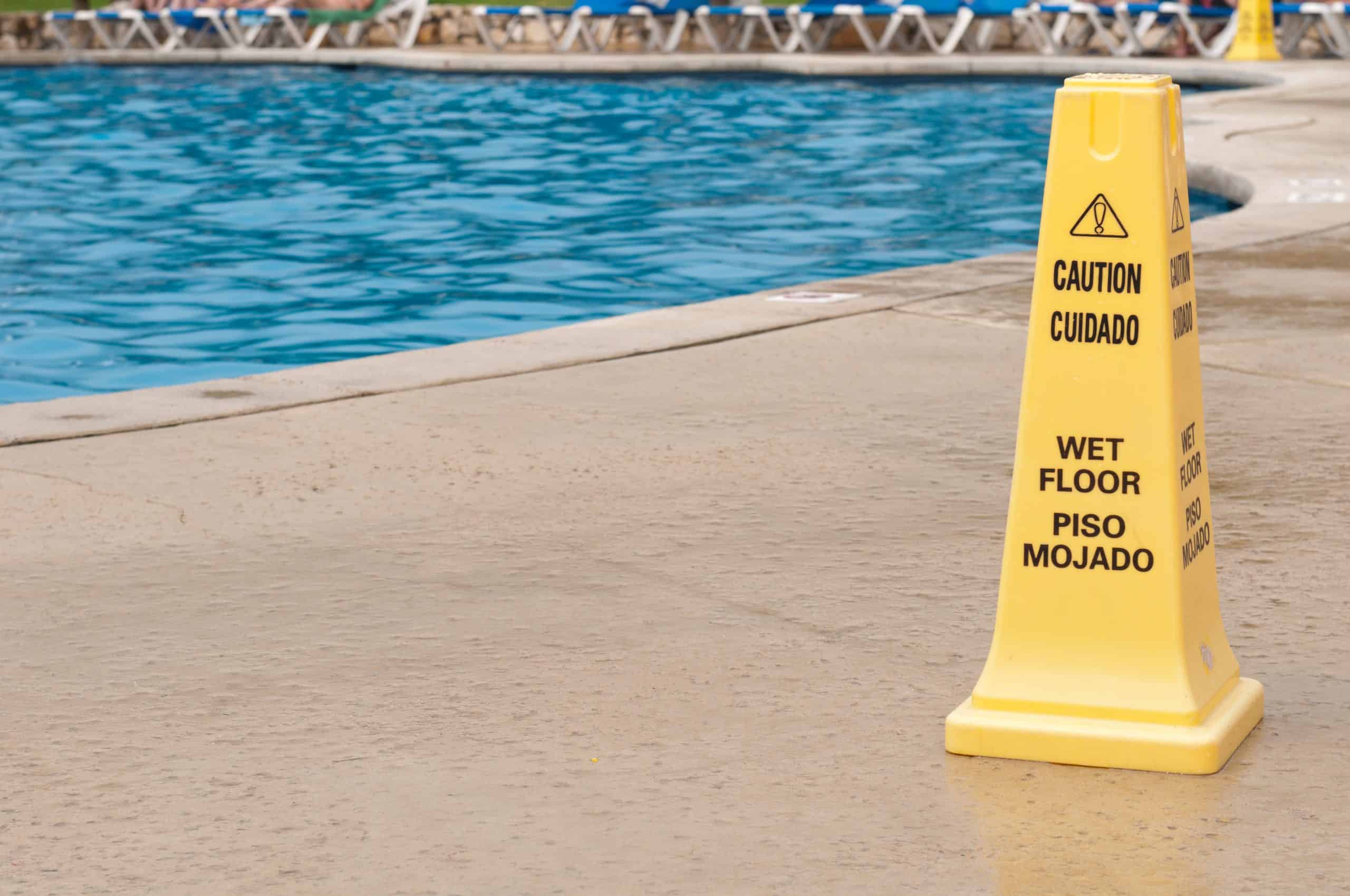 Wet floor sign ABC's of water- yellow caution sign regarding slippery surface next to a swimming pool (after a tropical storm)