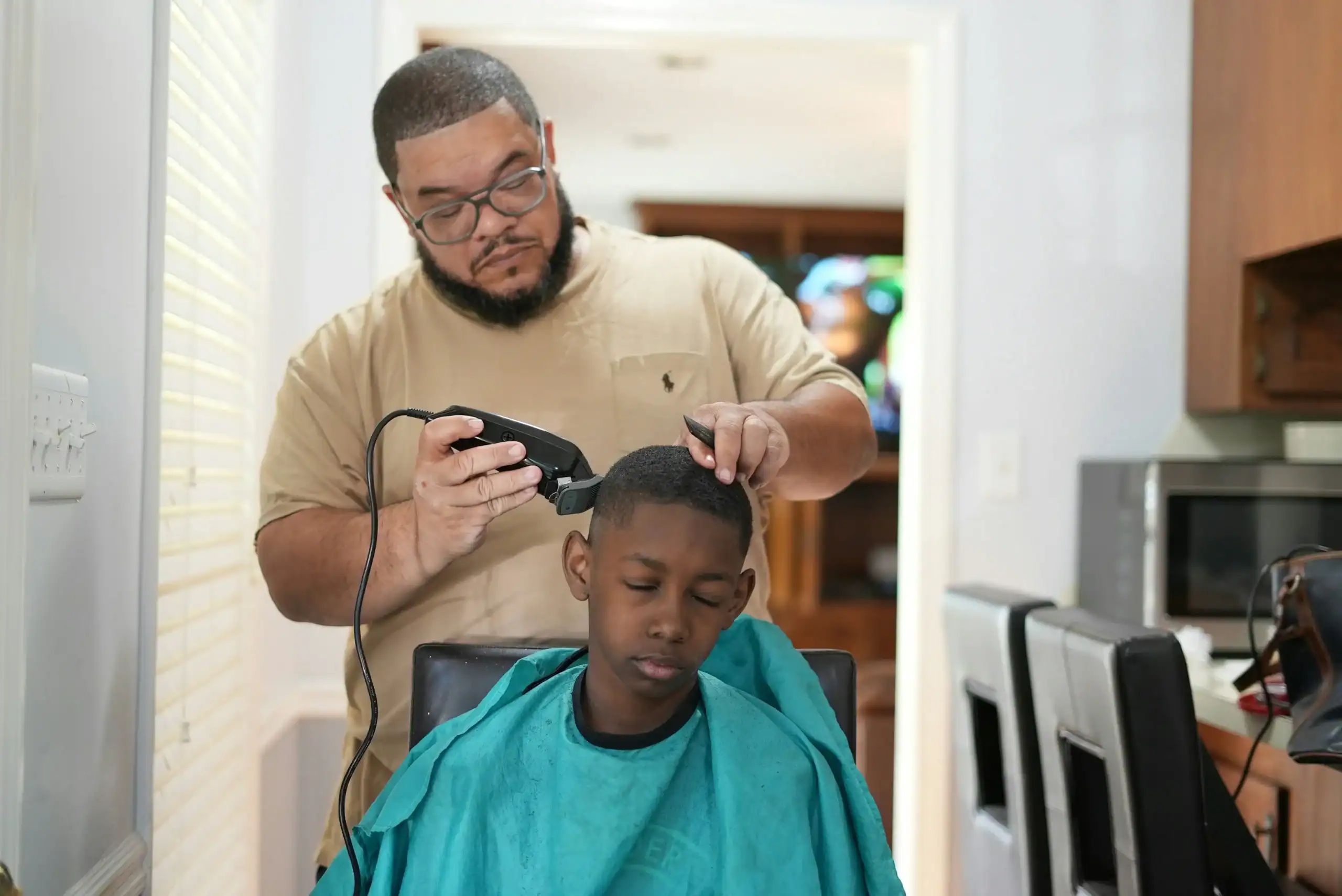 Dad giving son a haircut with clippers, a challenge for special needs haircuts.