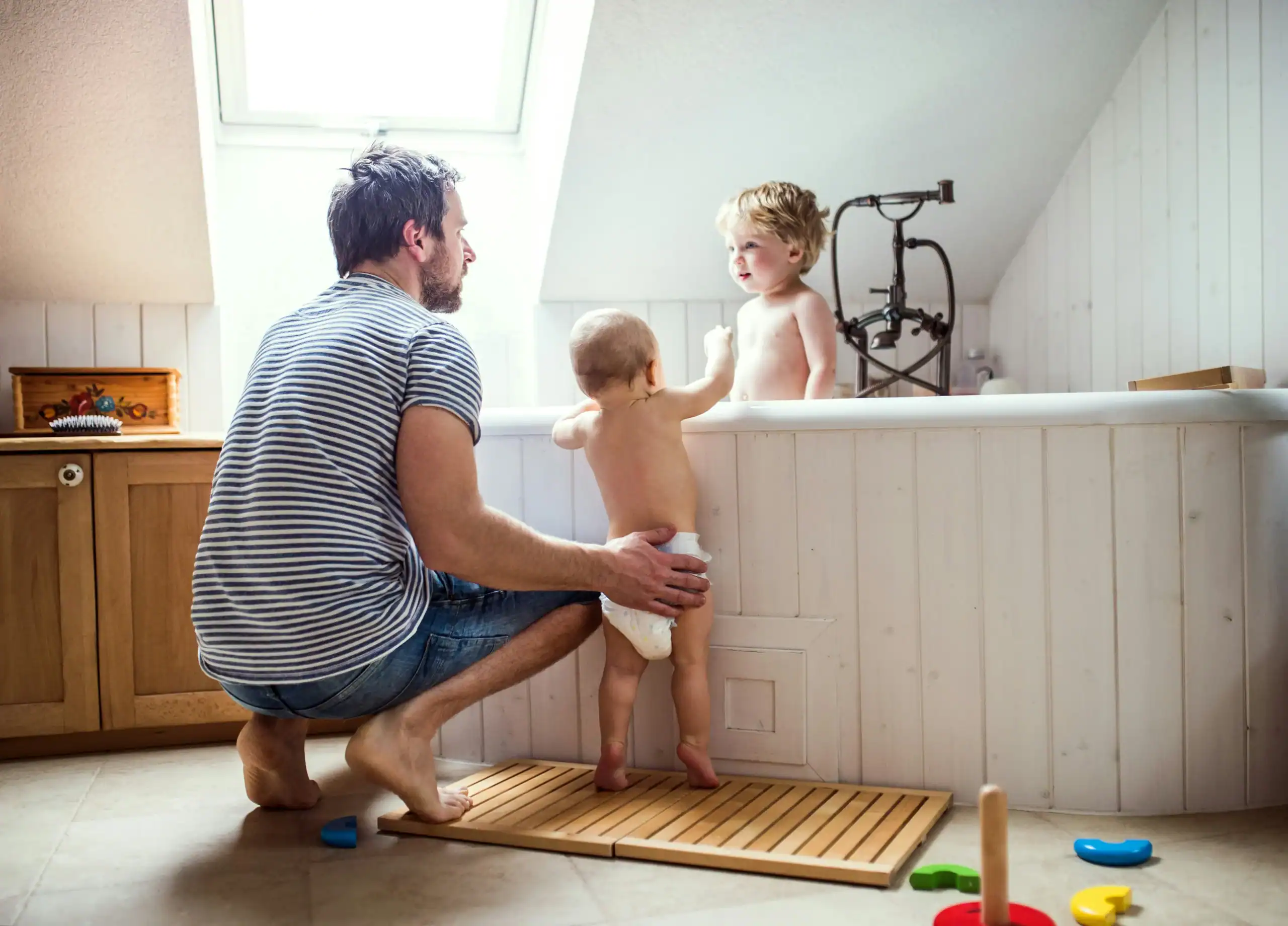 Father supporting two young children in the bathroom, helping with early potty training special needs routines. Father supporting two young children in the bathroom, helping with early potty training special needs routines.