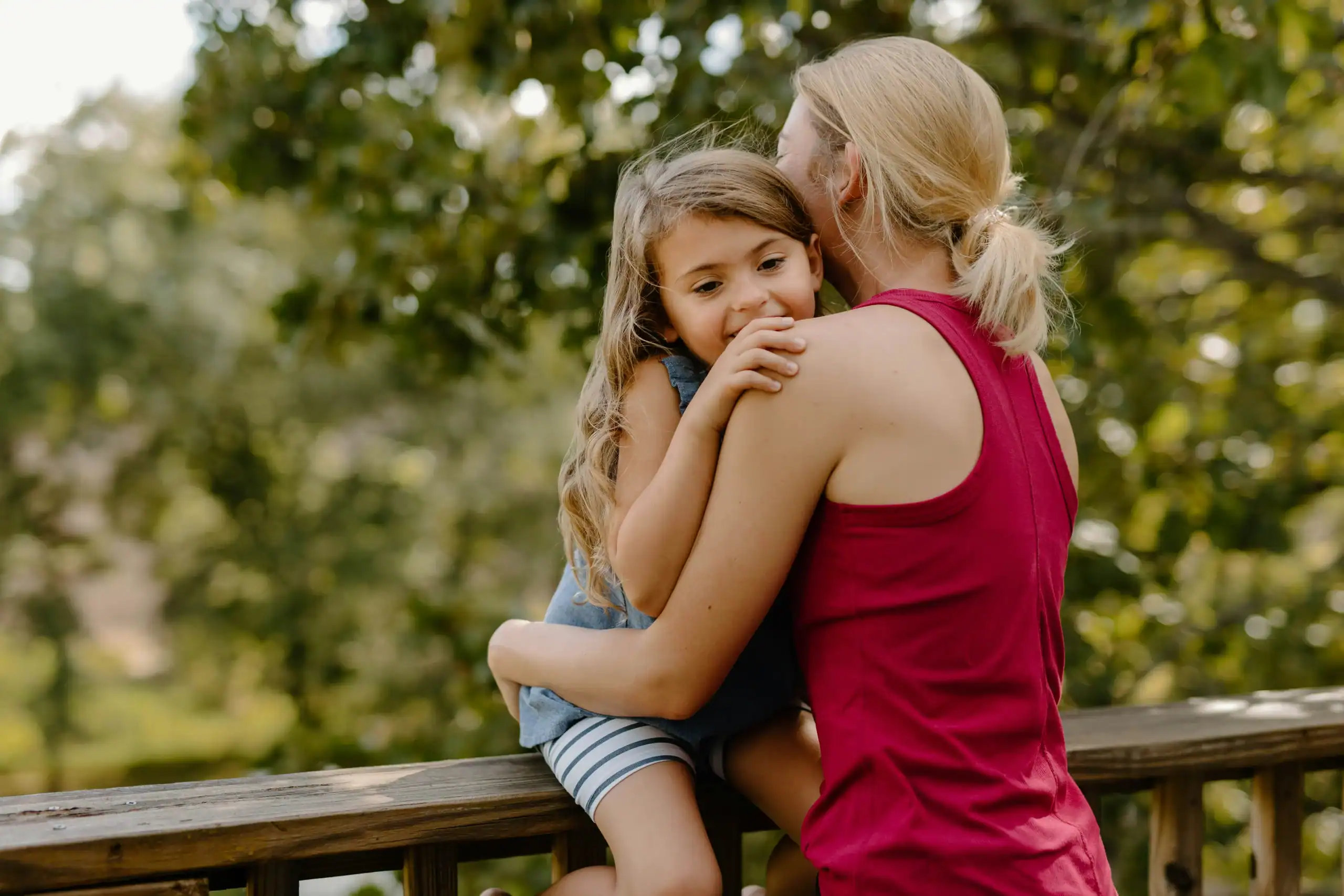 Mother comforting her daughter with rett syndrome and autism outdoors Mother comforting her daughter with rett syndrome and autism outdoors