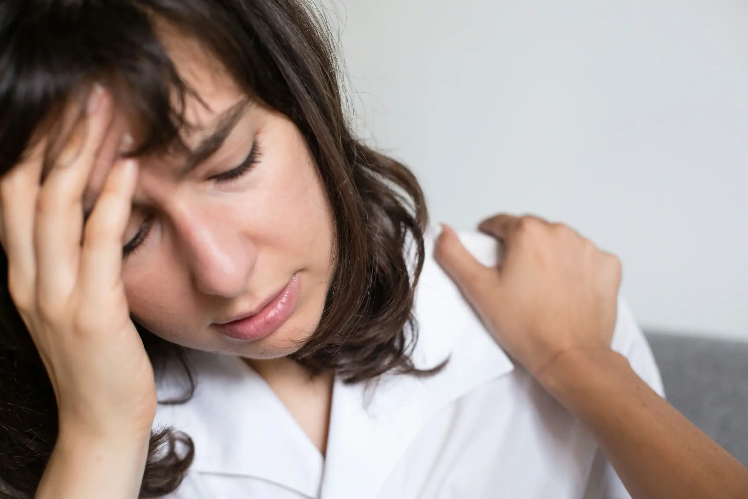 Overwhelmed woman comforted by a hand on her shoulder, showing caregiver burnout vs compassion fatigue impact Overwhelmed woman comforted by a hand on her shoulder, showing caregiver burnout vs compassion fatigue impact