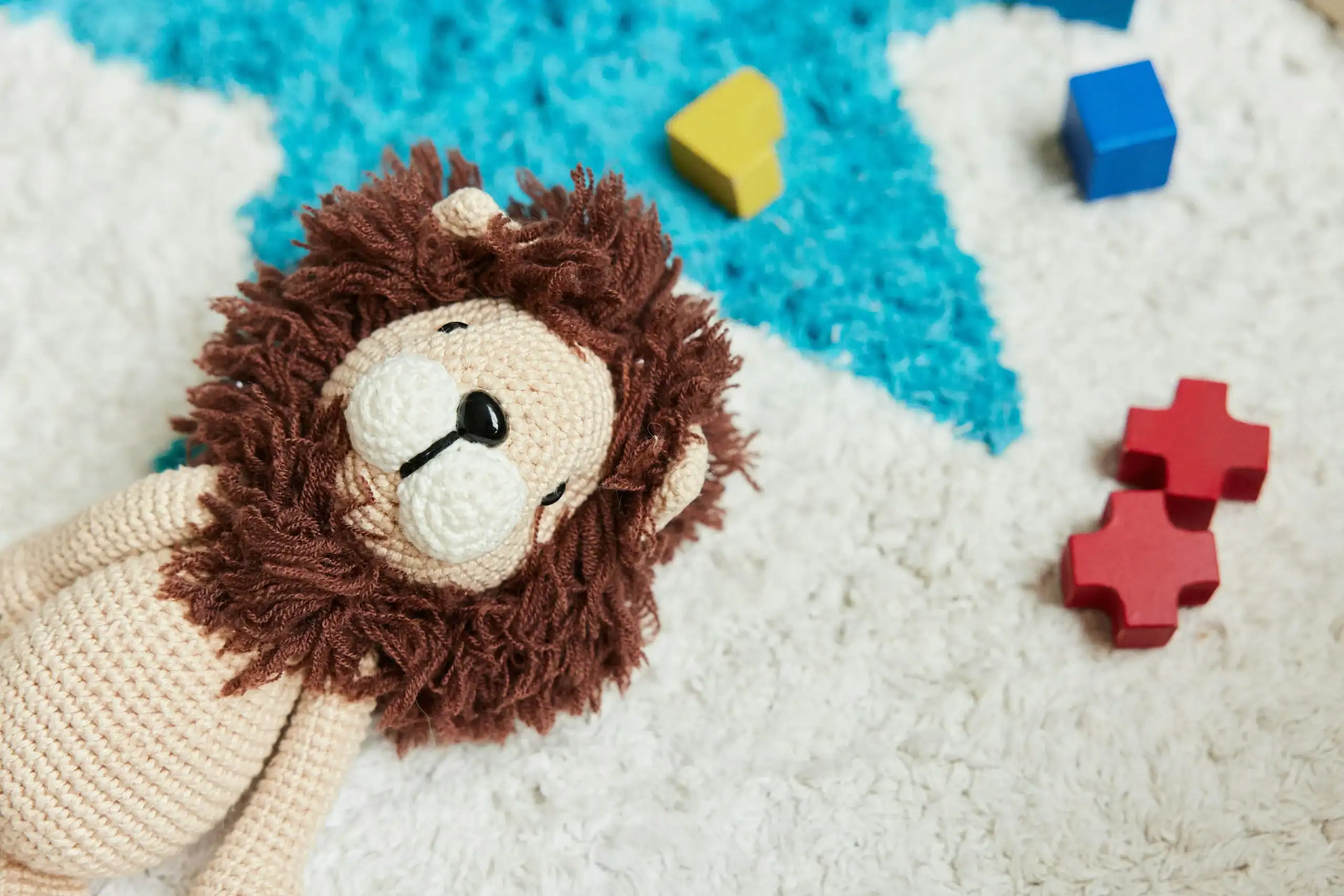 Soft toy lion on carpet used as comfort during special needs haircuts.
