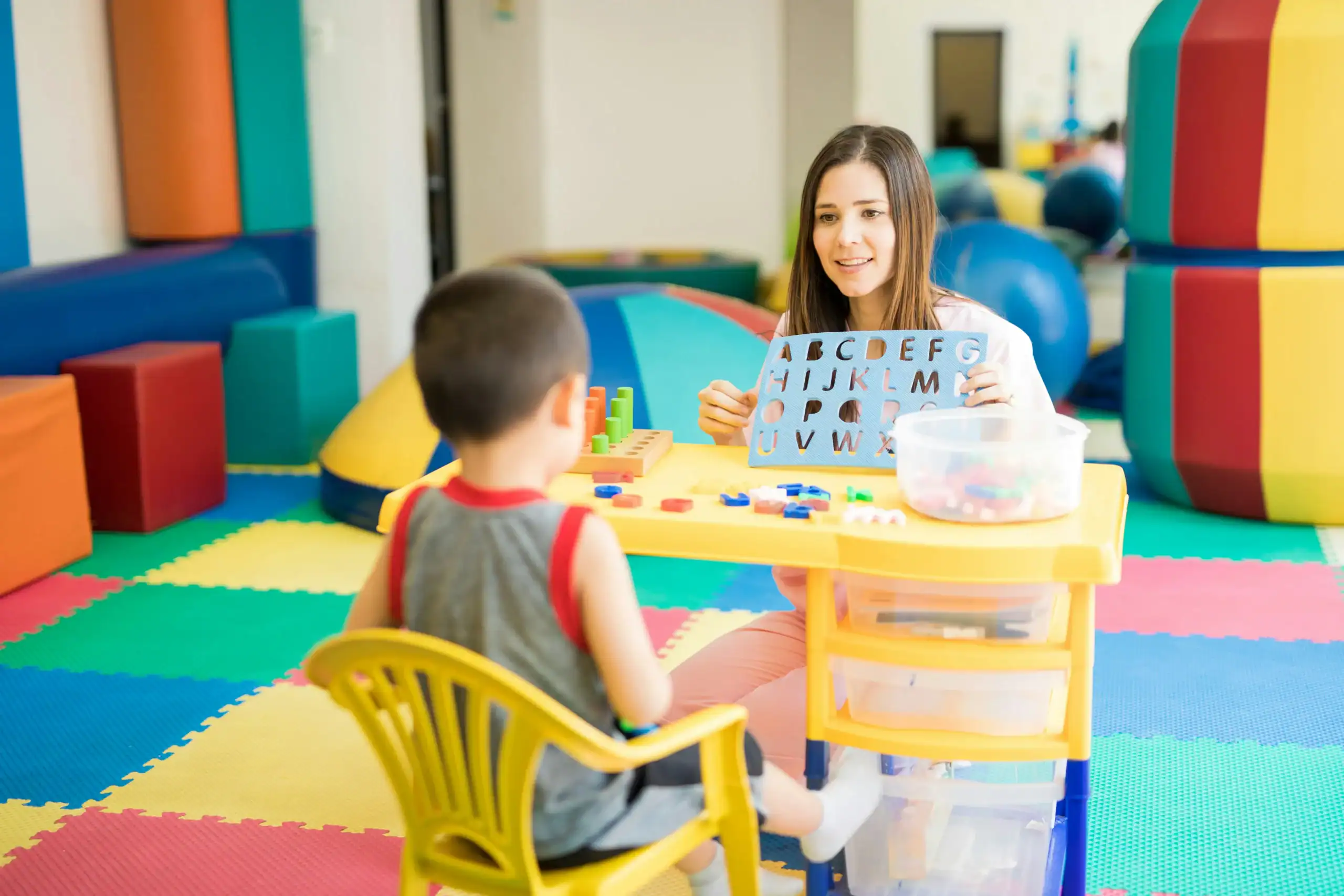Speech therapist helping a child with speech delay practice letters during therapy session. what is the most common cause of speech delay