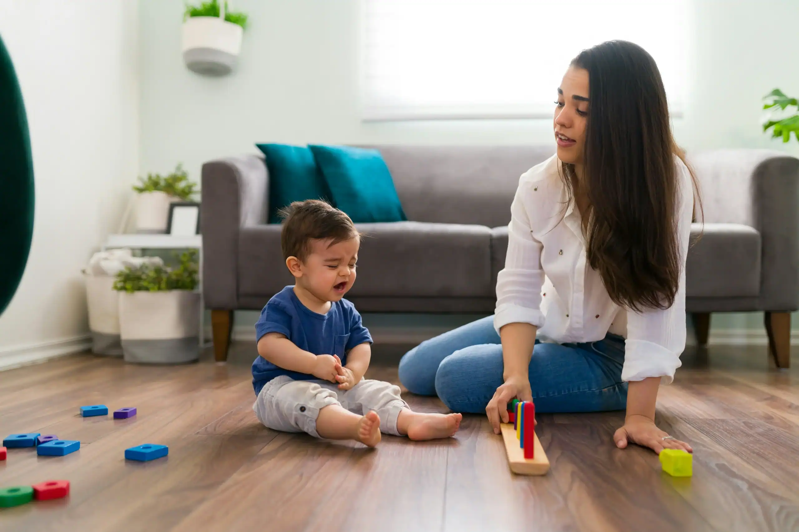 Parent helping toddler play with colorful toys at home, showing autism attachment to objects and early sensory learning.