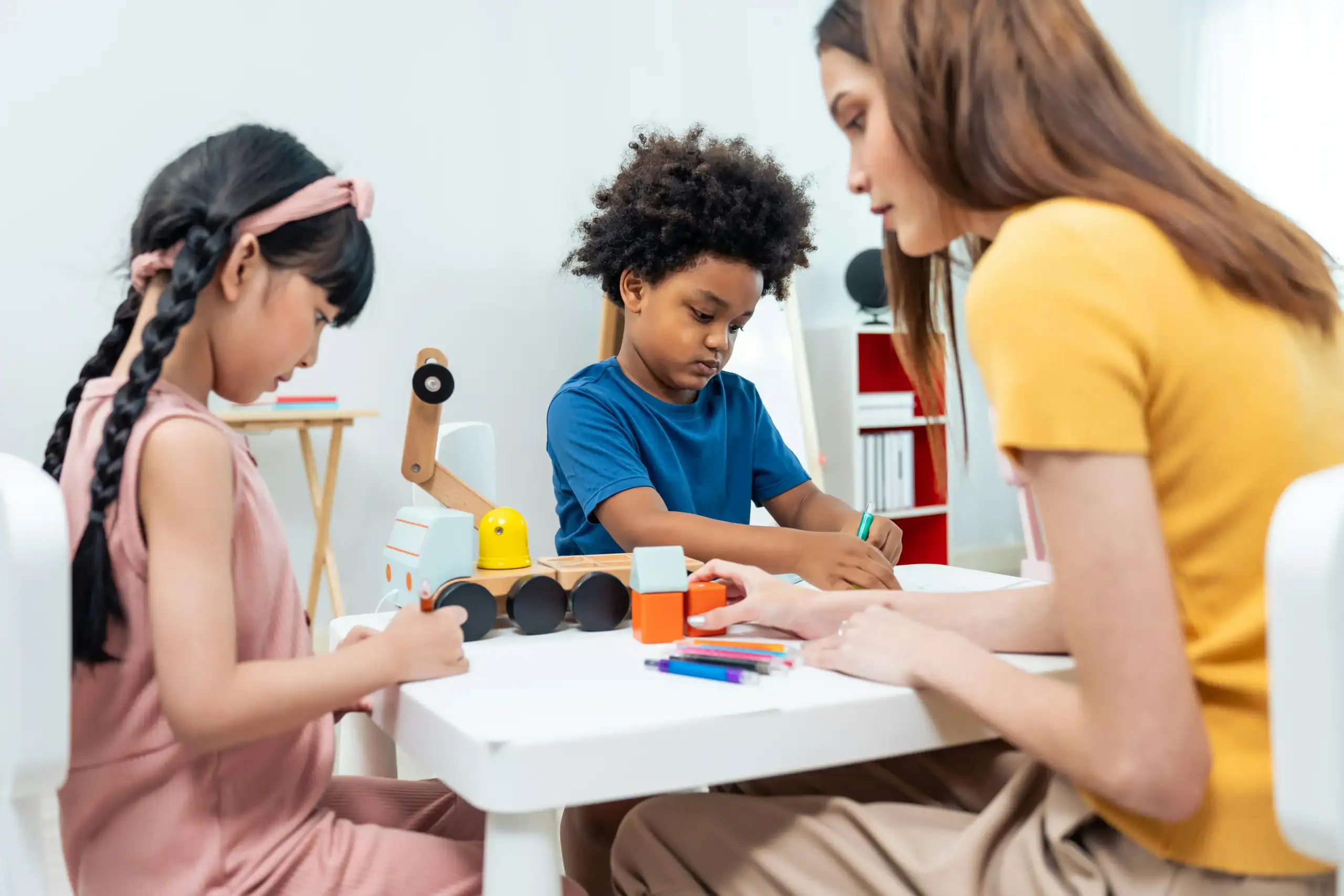 Teacher guiding children through focused play activities to reduce classroom autism behavior triggers. Teacher guiding children through focused play activities to reduce classroom autism behavior triggers.